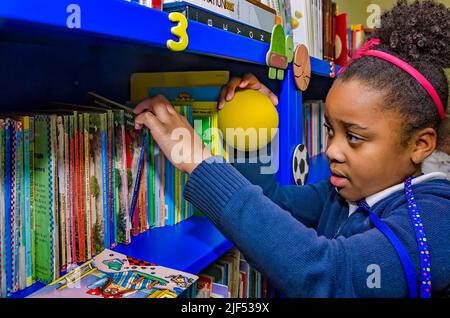An African-American girl chooses a book from a bookshelf during an after-school program, Feb. 28, 2013, in Columbus, Mississippi. Stock Photo