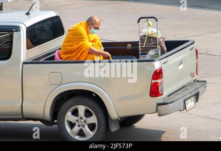 SAMUT PRAKAN, THAILAND, APR 07 2022, A Buddhist monk sits in the back of a moving pickup truck Stock Photo