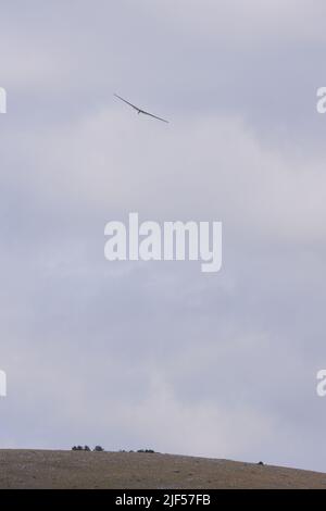 Glider flying high within dark clouds Stock Photo