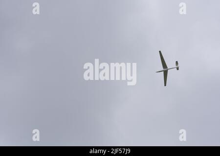 Glider flying high within dark clouds Stock Photo