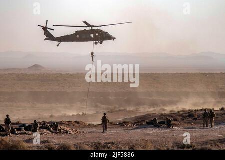 A Tunisian Armed Forces soldier conducts a fast rope descent from a UH-60 Blackhawk helicopter onto the battlefield during a combined arms live-fire exercise at the Ben Ghilouf Training Area in Tunisia, June 25, 2022. African Lion 2022 is U.S. Africa Command's largest, premier, joint, annual exercise hosted by Morocco, Ghana, Senegal and Tunisia, June 6 - 30. More than 7,500 participants from 28 nations and NATO train together with a focus on enhancing readiness for U.S. and partner nation forces. AL22 is a joint all-domain, multi-component, and multinational exercise, employing a full array o Stock Photo
