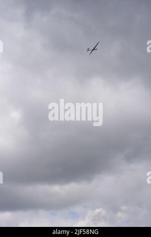 Glider flying high within dark clouds Stock Photo