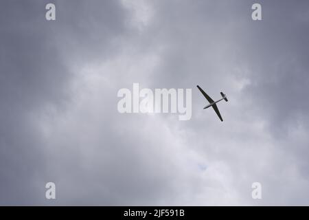 Glider flying high within dark clouds Stock Photo