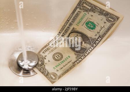 US dollar going down the drain in sink. Stock Photo