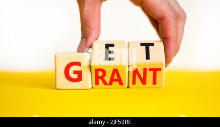 Get grant symbol. Businessman turns wooden cubes with concept words Get grant on a beautiful yellow table white background. Copy space. Business and g Stock Photo