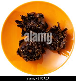 Tasty whole roasted artichokes served on plate Stock Photo