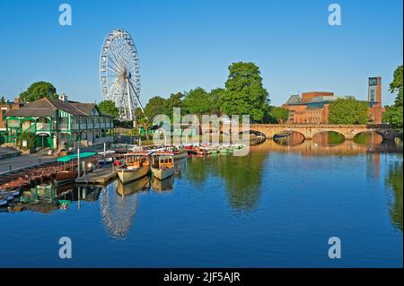 Boats moored on the River Avon Stratford upon AVON on a summer morning with the Tramway Bridge, Ferris Wheel and theatre reflected in the water Stock Photo