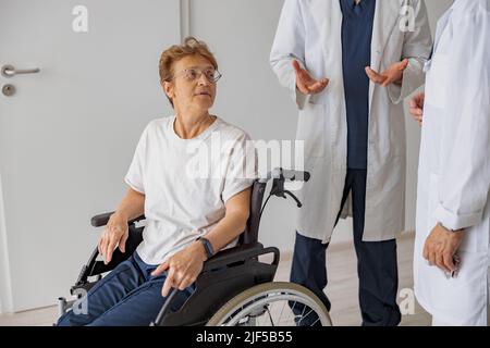 Professional doctors discuss over patient's diagnosis standing in hospital hall Stock Photo