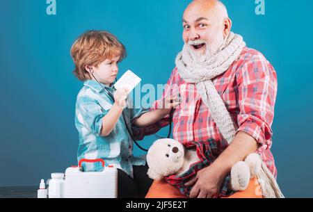 Healthy and health insurance concept. Boy doctor playing with dad. Elderly man with little cute doctor. Child boy stroking the head of the sick Stock Photo