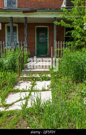 Entry to brick house overgrown with grass Stock Photo