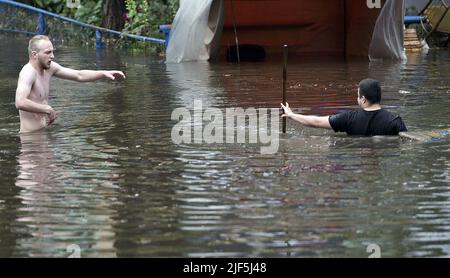 KYIV, UKRAINE - JUNE 29, 2022 - Men walk along a flooded street after the downpour, Kyiv, capital of Ukraine. This photo cannot be distributed in the russian federation. Stock Photo