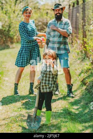 Farmars couple with son enjoy spring nature and take care about her plants. I love our moments in the countryside. Smile family on farmland. Stock Photo