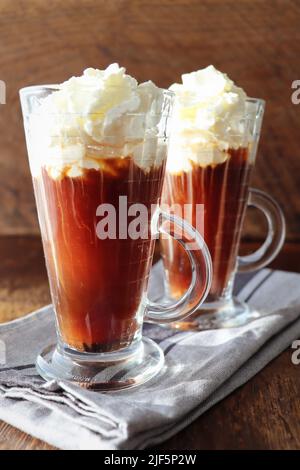 Irish Black coffee with whipped cream in a tall glass on a wooden dark background Stock Photo