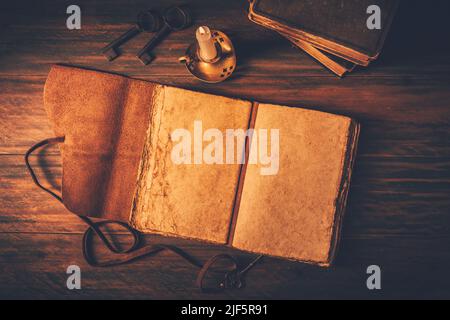 Blank antique leather-bound journal, book or diary with old books and candle Stock Photo