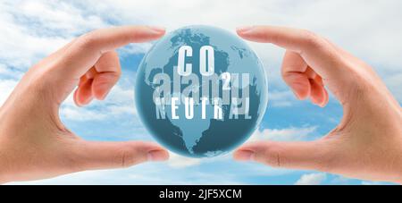 Carbon neutral concept. Hand holding CO2 neutral in globe map on blue sky and white clouds background. Environment day. Carbon neutral web banner. Stock Photo