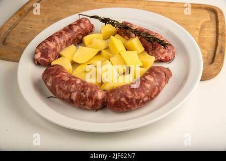 Link sausages with fresh baked potatoes on wooden cutting board   isolated on white with copy space. Stock Photo