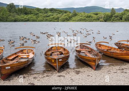 Wooden rowing boats for hire line the shore of Derwent Water at Keswick in the Lake District, Cumbria Stock Photo