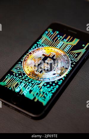 Bitcoin logo on a phone screen against a leather background Stock Photo