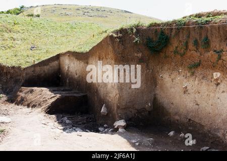 Archaeologists dug a hole on hillside to search for historical artifacts and finds. Archaeological work. Stock Photo