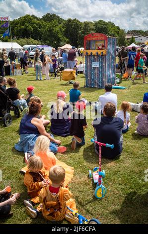 Families watch a traditional Punch & Judy puppet show at Billingshurst Show in West Sussex, UK. Stock Photo