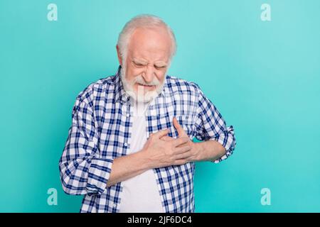 Picture of old pensioner grandfather touching chest suffering from heart attack isolated on teal color background Stock Photo