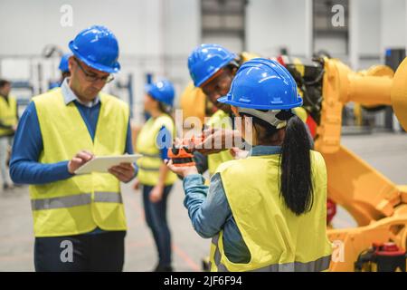 Multiracial engineers working inside robotic factory - Focus on woman helmet Stock Photo