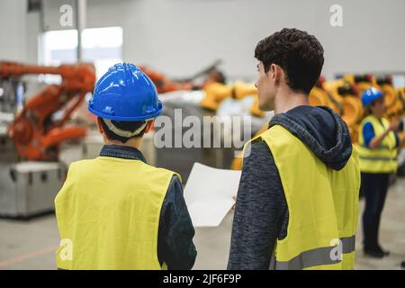 Industrial engineers working inside robotic factory - Focus on man face Stock Photo