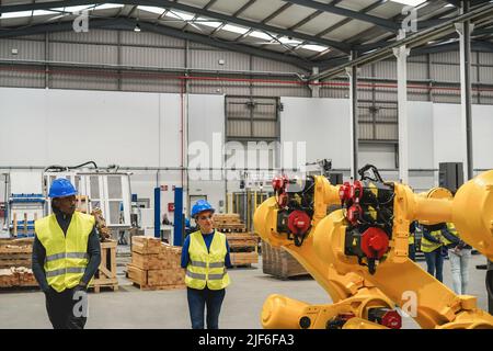 Industrial engineers working inside robotic factory - Focus on robot machine Stock Photo