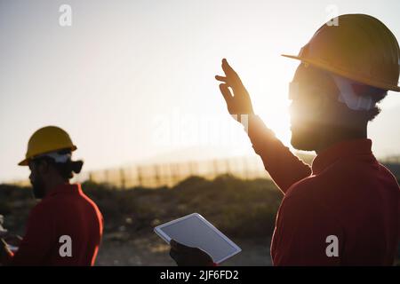 Engineers using futuristic virtual reality glasses while working on windmill farm with digital tablet - Renewable energy concept Stock Photo