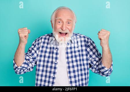 Photo of cheerful overjoyed ecstatic granddad raise fists in victory triumph win lottery isolated on teal color background Stock Photo