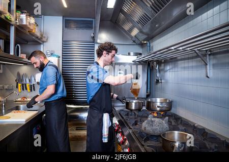 Side view of male chefs preparing food in commercial kitchen Stock Photo