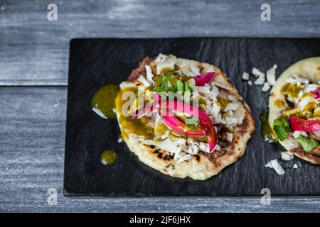 From above delicious traditional Yucatan panuchos with chicken and beans garnished with green sauce and pickled red onion and served on black slate Stock Photo