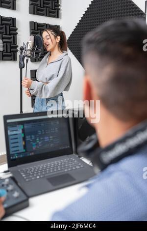 Young female singer recording voice in mic at music studio Stock Photo