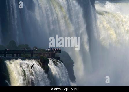 Tourists watching Devil's Throat from the Brazilian side of Iguazu Falls on the border between Brazil and Argentina. Stock Photo