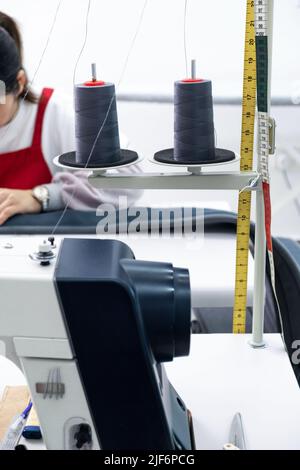 Anonymous cropped dressmaker in uniform sewing on machine while working ...