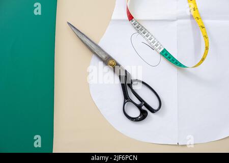 Top view of metal scissors and colorful measuring tape placed on paper pattern on table in light workshop during sewing Stock Photo