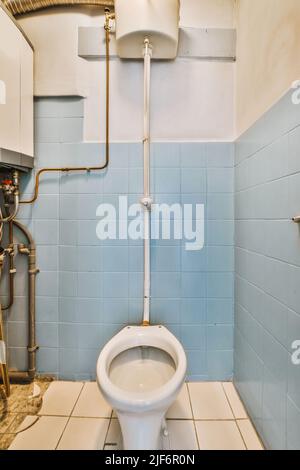 Old weathered toilet in bathroom with blue tiled walls Stock Photo