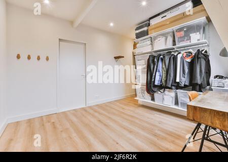 Comfortable chair placed near table near open wardrobe in light home office in contemporary flat Stock Photo