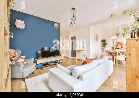 Interior of stylish living room with comfortable sofa and armchairs with cushions placed on carpet around table in modern apartment