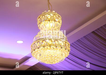Beautiful crystal chandelier hanging from the ceiling in the interior with lights Stock Photo