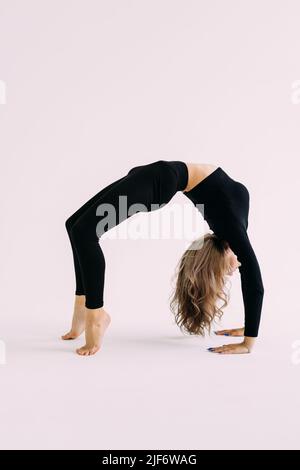 Portrait of sporty beautiful young brunette woman in sportswear bra and black pants working out, doing Purvottanasana, Reverse Plank Pose, studio full Stock Photo