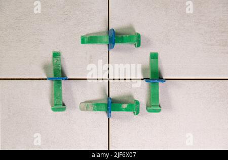 Aligning ceramic tiles on the wall in the bathroom. Self-leveling system for tiles. Stock Photo