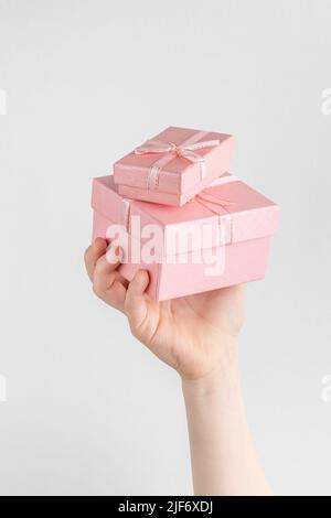 Child hand holding two gift boxes with pink bow. white and gray background with copy space Stock Photo