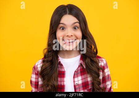 Funny kids face. Portrait of silly teenager child girl smiling and showing tongue in camera making funny faces. Stock Photo