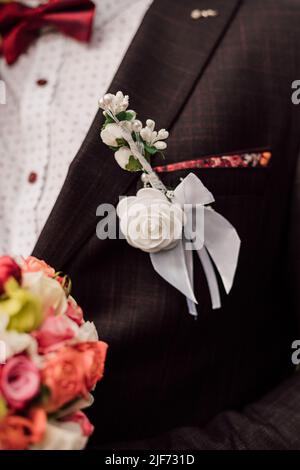 Closeup of boutonniere with the decor on a grooms black elegant