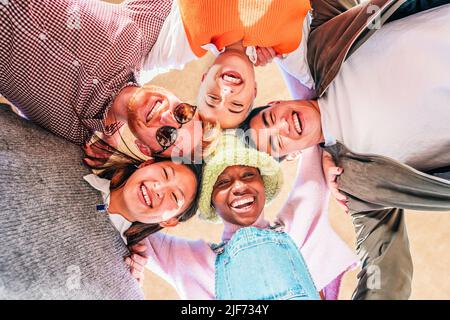 Low angle view of young multiethnic friends standing together smiling and having fun. Stock Photo