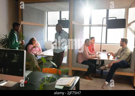 Multiracial male and female colleagues discussing while having coffee during break in office Stock Photo