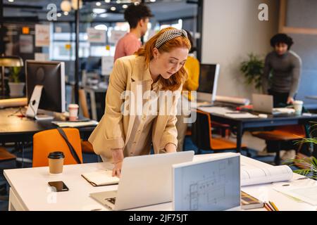Caucasian young businesswoman working on laptop at desk in creative office Stock Photo