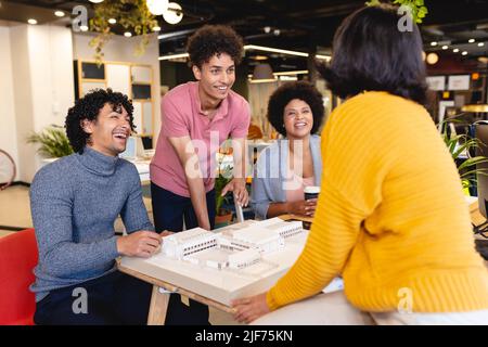 Smiling multiracial male and female architects discussing over architectural model in office Stock Photo