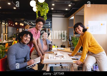Portrait of smiling multiracial male and female architects with architectural model in office Stock Photo
